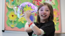 Young person wearing hospital bracelet holding tambourine